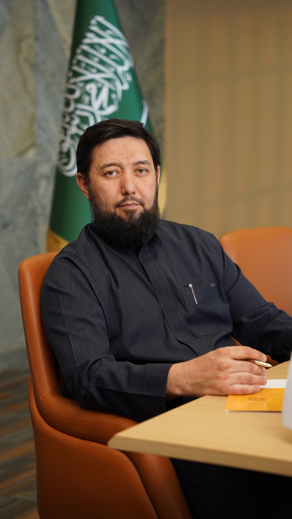 Rustam Khaitmetov at the Madinah office, the Saudi flag behind