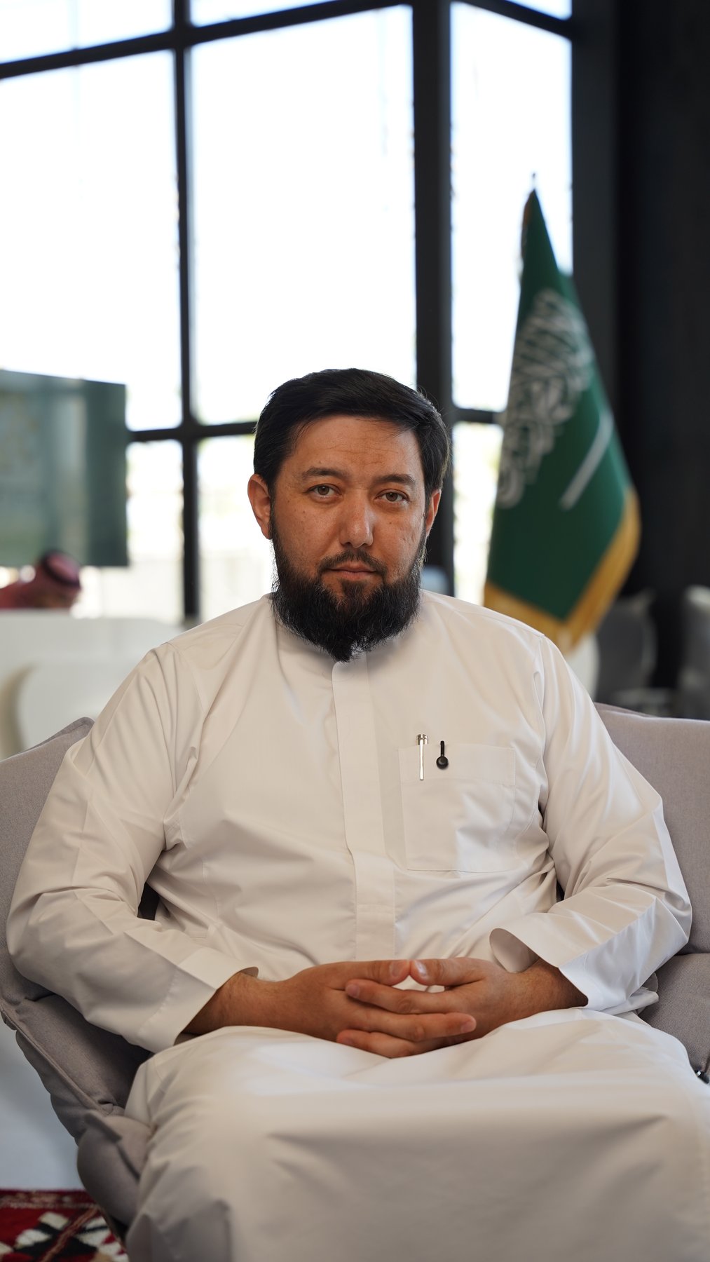 Rustam Khaitmetov seated in white, at the office majlis