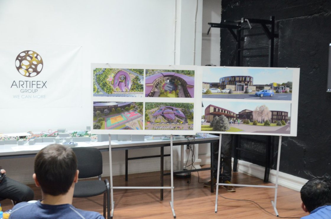 Project boards on easels beside a site model, set up for a review in the ARTIFEX GROUP studio